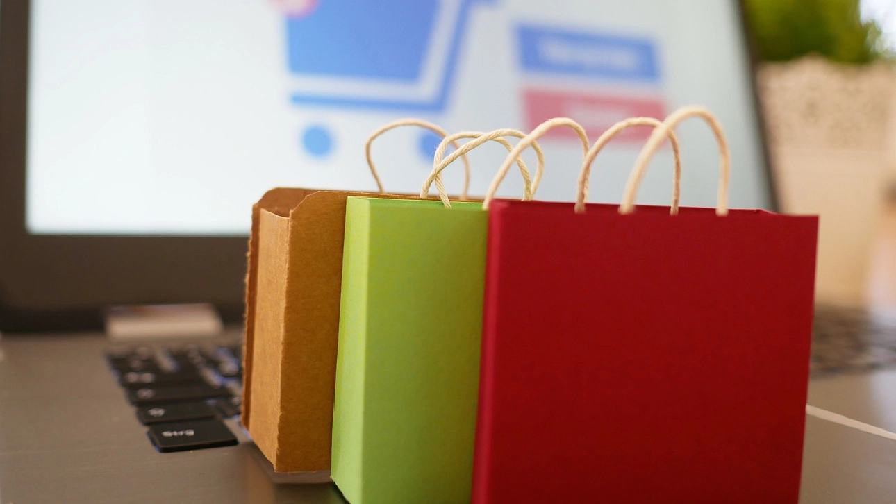 Colorful shopping bags on a laptop keyboard, symbolizing eCommerce store launch preparation.
