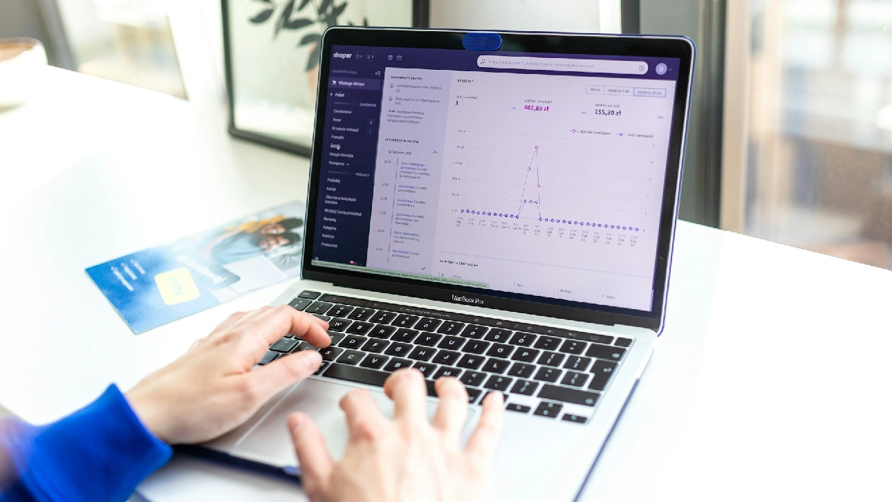 Hands on laptop displaying Shopify dashboard analytics, illustrating eCommerce development workflow.