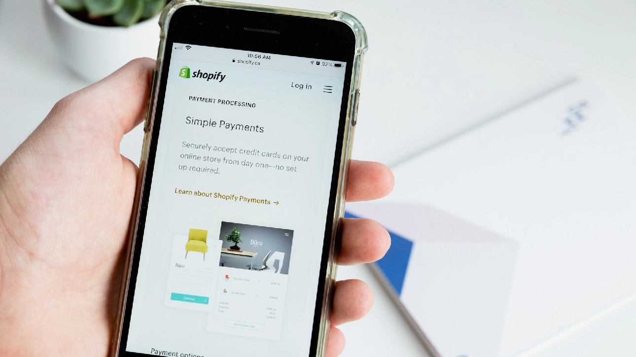Hand holding smartphone showing Shopify Payments setup screen, representing key steps in Shopify development checklist.