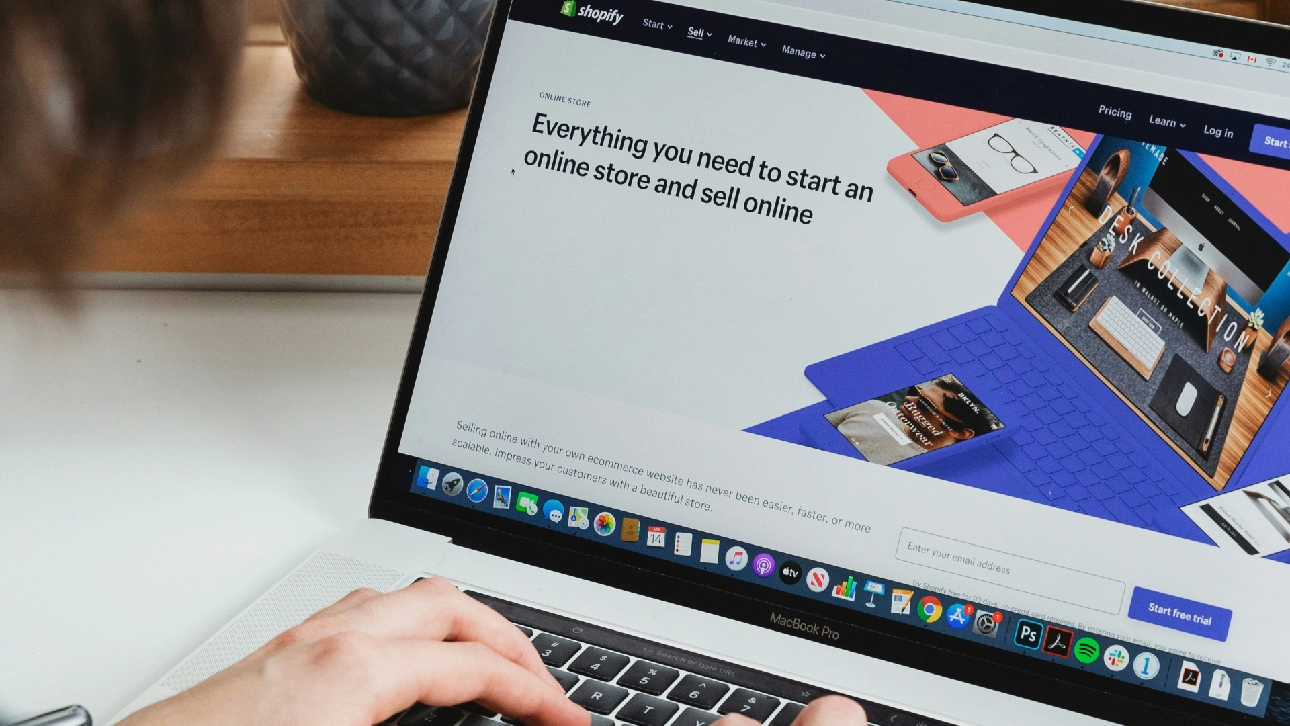 Person using a MacBook Pro to view Shopify’s homepage promoting online store setup and selling features.